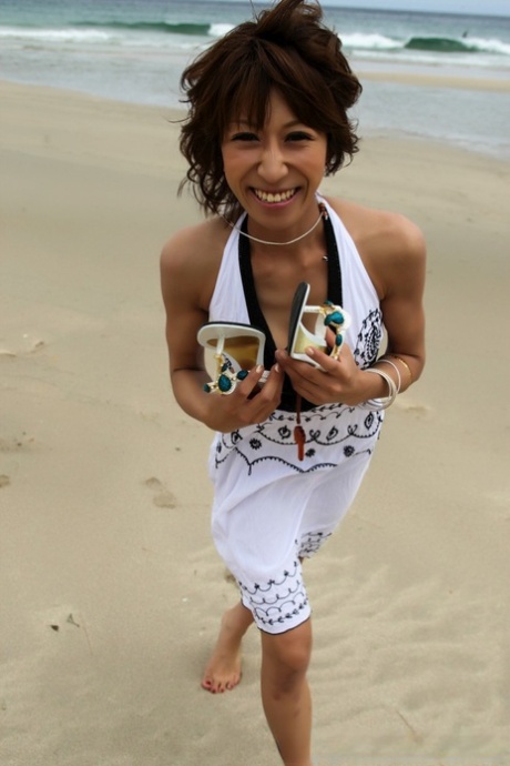 In the middle of the ocean, a Japanese girl plays in her bikini while enjoying the beach.