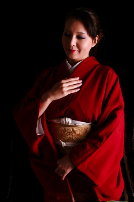 Red lips are present as a Japanese woman in traditional clothing making a knife.