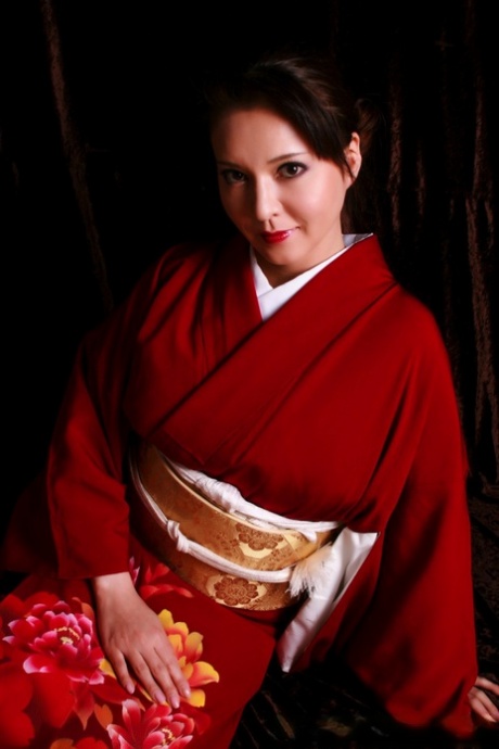 Wearing traditional clothing, a Japanese woman displays her red lips while making a knife.