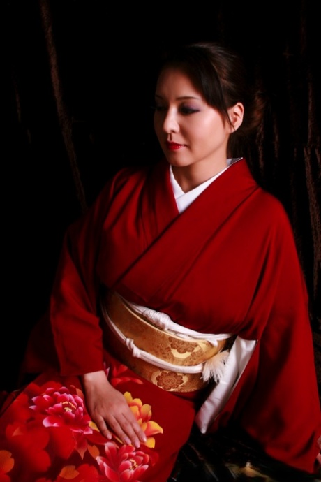 Traditional clothing of a Japanese woman with red lips and holding a knife.