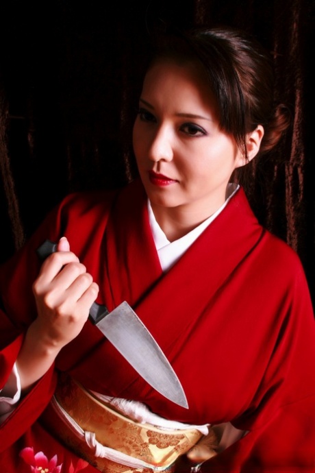 A woman in Japanese fashion wears her traditional outfit while producing a knife, with her lips appearing red.