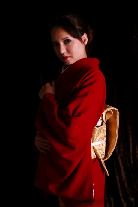 Using a knife in traditional attire, the Japanese woman has red lips.