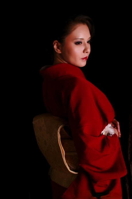 In the traditional outfits, a Japanese woman produces a knife while wearing red lips.