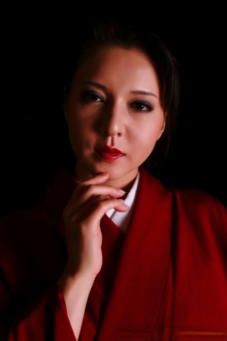 As she creates a knife in traditional attire, the Japanese woman has red lips on her face.