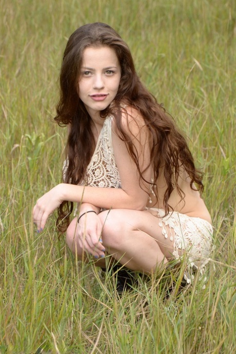 Iva Nora's long hair catches her eye as she plays in a field, making it an interesting scene.