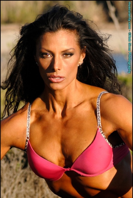A dark-haired bodybuilder named Deidre Pagnanelli can be seen putting on bras on her shoulders to show off the straps.