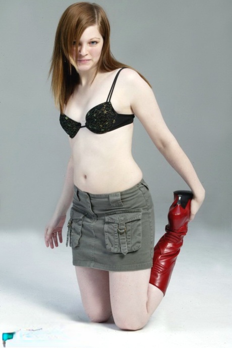 With her pale red hair, Lilly slowly switches between a black G-string and red leather boots.