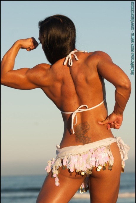 Tram Nguyen, an Asian bodybuilder, displays her muscle power on a beach while wearing bikinis.