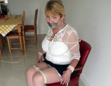Blonde woman taunted with duct tape while her tits were fastened to the floor by rope.