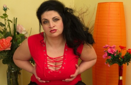 An overweight woman who is a housewife puts on her clothing and wears alluring hosiery while indulging in her vagina.