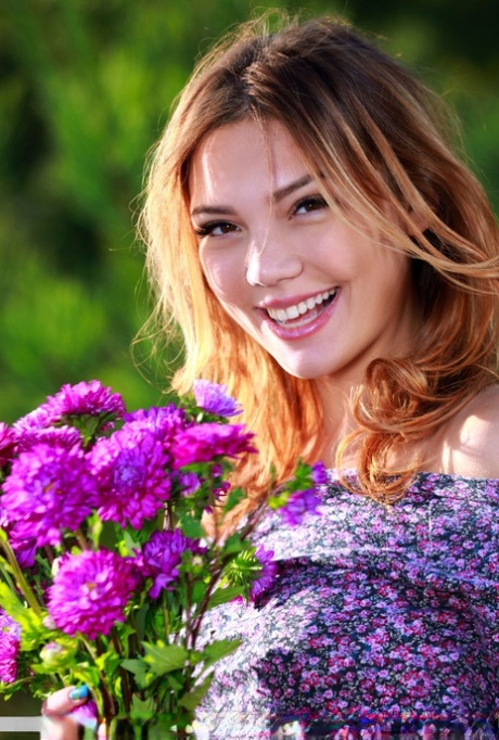 Alicia Love, the beautiful Asian girl in the photo, is holding onto a bunch of flowers before taking a naked look.