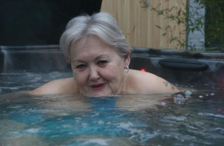 Chubby nan, who is naked in an outdoor hot tub, exhibits her pussy and tits through the photo.