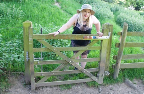 Under a tree, blonde BBW makes her debut in the nude, donning a safari hat.