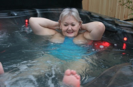 An elderly woman engages in hot tubing and plays with her breasts during Valgasmic Exposed.
