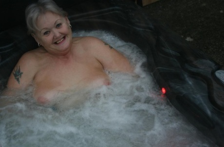The Valgasmic Exposed, a mature woman, enjoys hot tubing while playing with her breasts.
