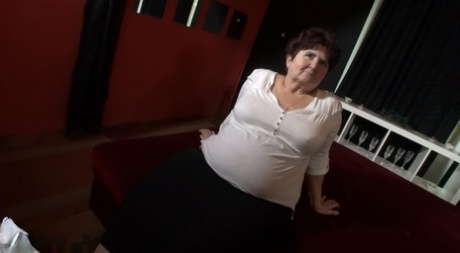 On a bed, an overweight grandmother engages in POV sex.