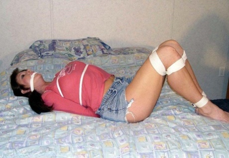 This is a picture of a Caucasian girl in clothing, with her clothes tied up and left hanging on a bed.