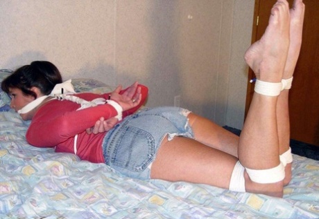 This is a picture of a Caucasian girl in clothing, with her clothes tied up and left hanging on a bed.