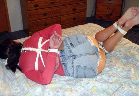 This is a picture of a Caucasian girl in clothing, with her clothes tied up and left hanging on a bed.