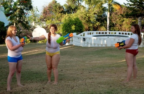 In the yard, white t-shirts are soaked with water guns made of high-sodium by girls wearing big t-shirts.