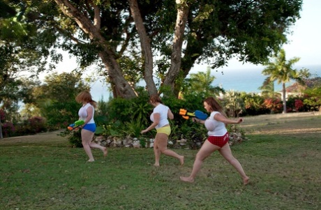 White t-shirts of girls with big t-shirts are soaked in water guns that are super-soaking and secured.