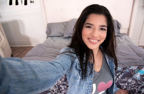 Gabriela, a brunette amateur, displays her prominent breasts by taking off the top of a jean jacket.