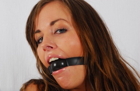 The pretty girl then cuffs her wrists together after doing a ball gag.