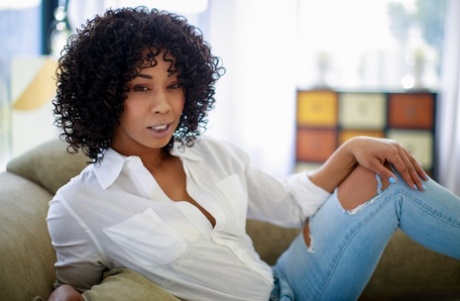 A beautiful black girl named Misty Stone appears completely naked on a chaise lounge.