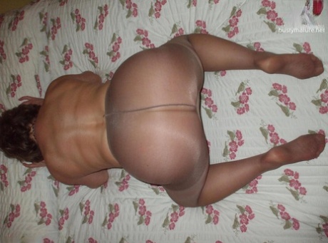 Busty Bliss, a slim and mature woman, removes her pantyhose to expose a complete naked image in a model.