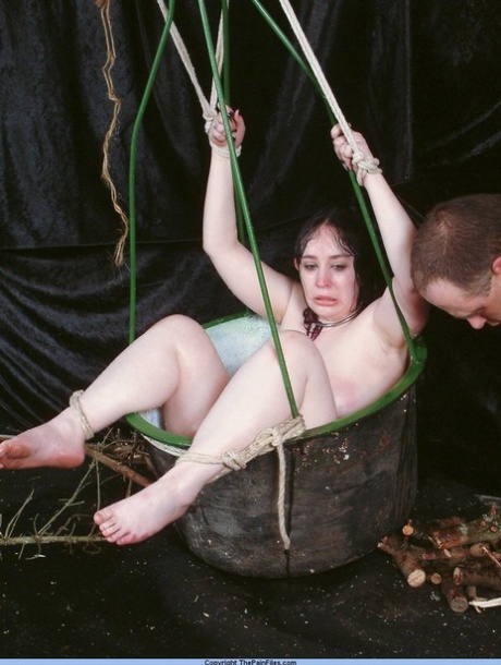 During needle play, an overweight female sexual captive is restrained in a basket.