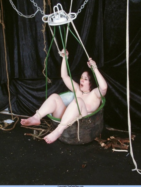 While performing needle play, a woman who is an overemphatic sex slave is restrained in a basket.