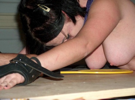 The backside of a girl with dark hair is covered in hot wax during her bondage.