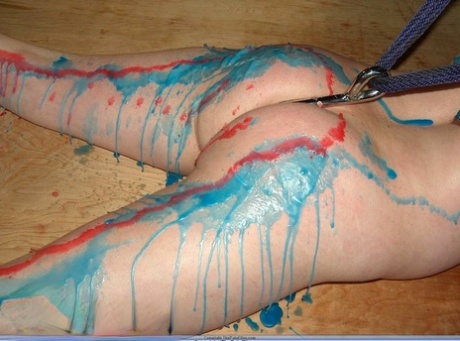 The backside of the dark-haired girl is soaked with hot wax during her tattooing session.