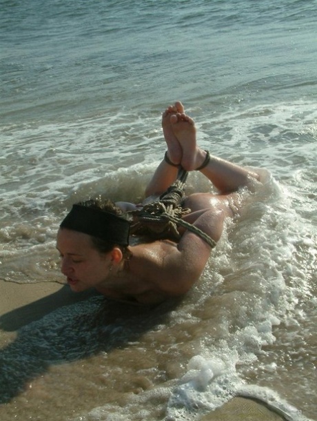 When surf arrives, the lesbian lover of a naked girl is seen tied up with rope by her partner.