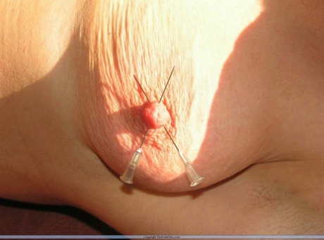 Using needles, a restrained Caucasian woman has her nipples pinched.