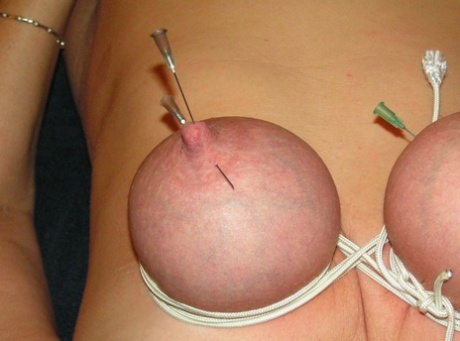 A blonde woman has her breasts and nipples needled in her.