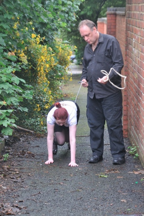 Before crawling on all fours, Redhead licks her Master's boots in the parking lot.