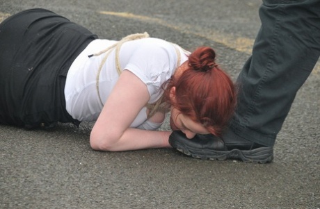 Redhead licks her Master's boots in the parking lot before crawling on all fours.