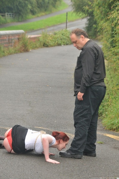 Prior to crawling on all fours, Redhead licks her Master's boots in the parking lot.