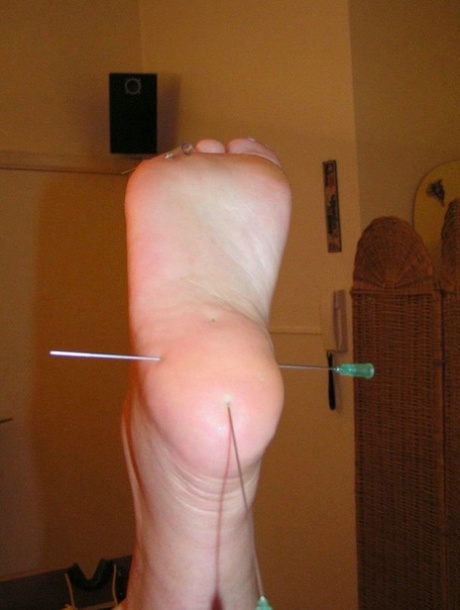 Needles are inserted into various body parts of the restrained white girl.