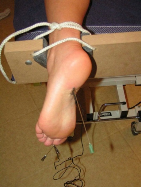 A white girl who is restrained has needles inserted into different body regions.