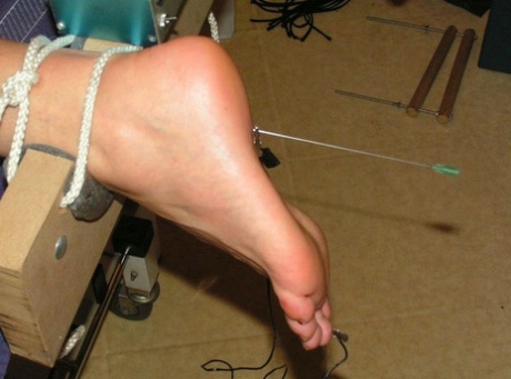 Needles are inserted into various body parts of the restrained white girl.