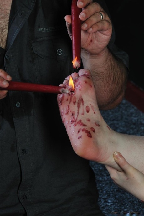 Hot candle wax is used to torture a fat redhead by an individual who practices sadistic behavior.