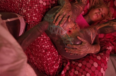 An asshole with extensive tattooed hands is stretched out by a heavily tattooed woman using her fingers to close it.