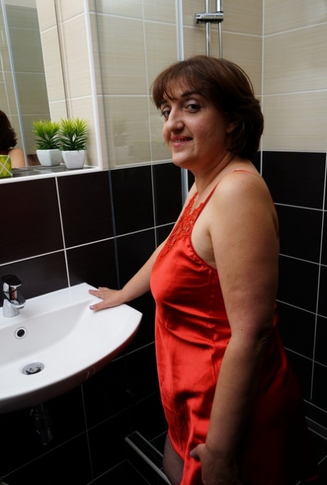 The older woman reveals her big belly button moments before masturbating in the shower.