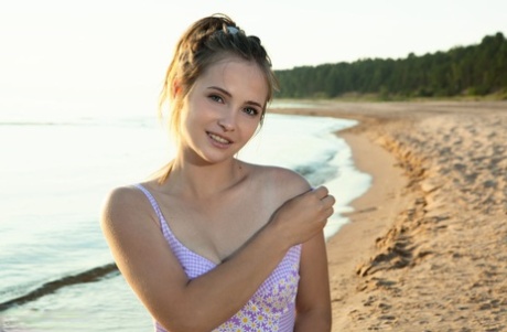 Teen Lit removes her swimsuit to pose in the nude on a beach blanket.