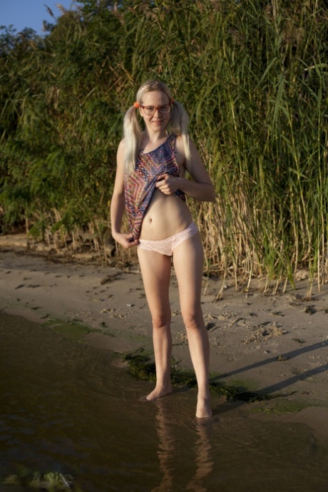 After wading into a lake without clothes on, Nerdy amateur Nika splashes water.