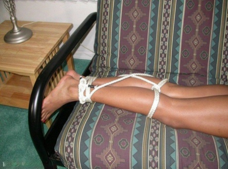 Long-legged black girl on futon gets hogtied and gagged.