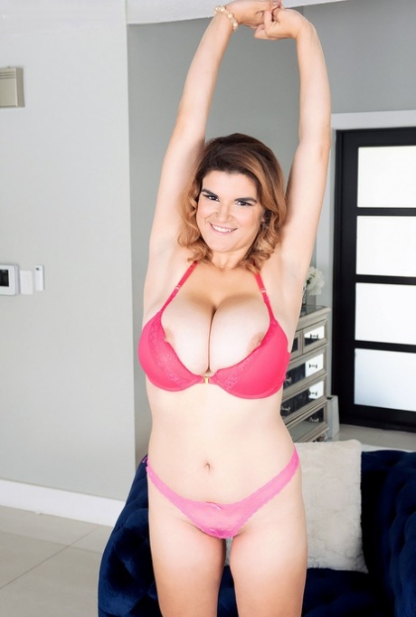 Posing fun in a pink bikini top, Jenni Noble displays her large breasts.