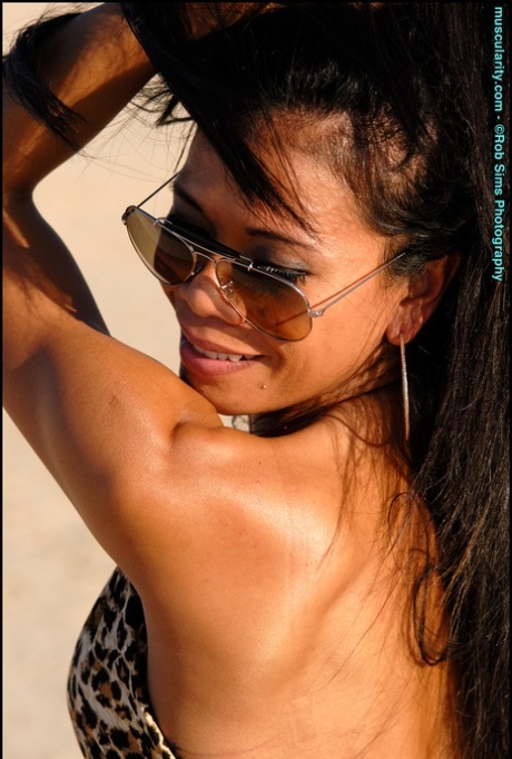 On a deserted lake bed, Alma Villanueva, an Asian bodybuilder, models herself in shades.